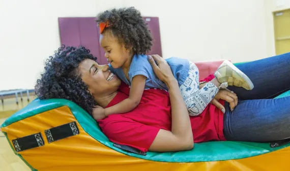 A childcare worker playing with a young girl. 