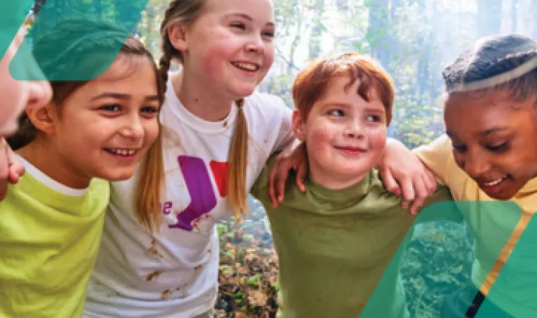 A group of YMCA campers in a group huddle before a fun outdoor camp activity.